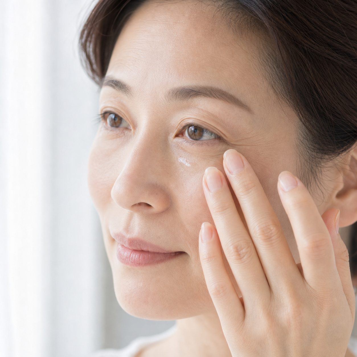 目元に美容液をなじませる指先